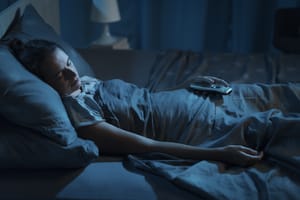 Woman sleeping with light of her TV on